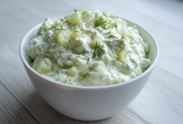 A white bowl filled with creamy dill pickle dip, garnished with fresh dill sprigs.