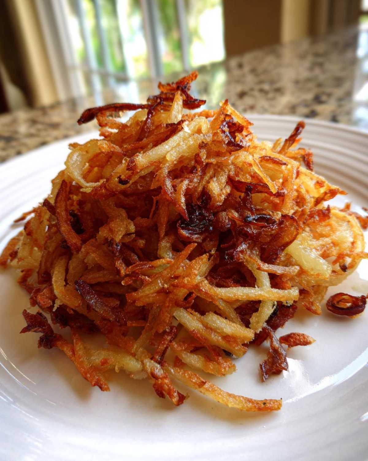 A mound of golden brown, crispy fried potatoes piled high on a white plate.