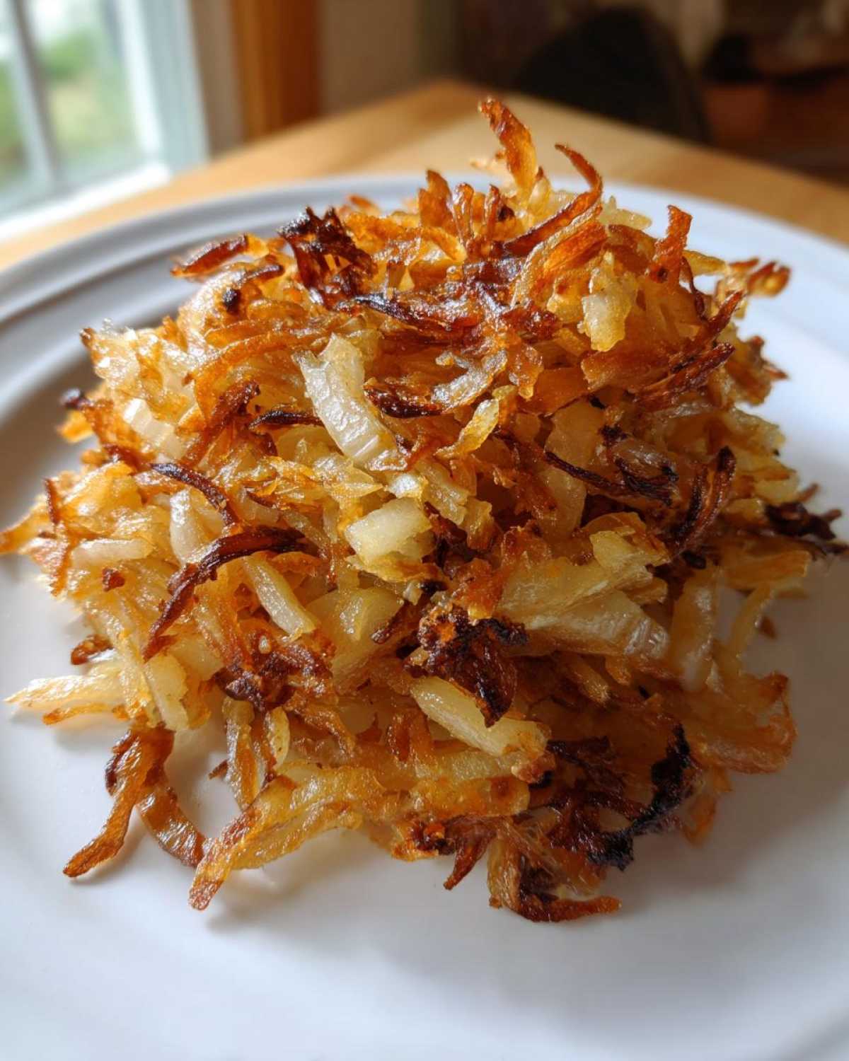 A close-up of a mound of golden brown, crispy fried potatoes served on a white plate.