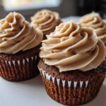 Close-up of rich, dark gingerbread cupcakes topped with swirls of spiced cream cheese frosting.