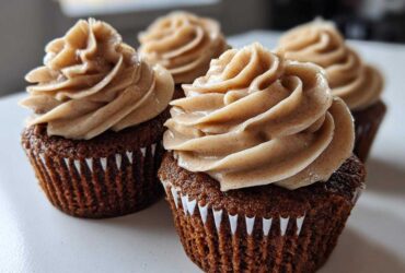 Close-up of rich, dark gingerbread cupcakes topped with swirls of spiced cream cheese frosting.