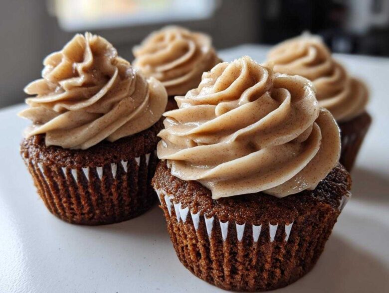 Close-up of rich, dark gingerbread cupcakes topped with swirls of spiced cream cheese frosting.