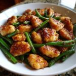 Close-up of delicious, glazed chicken pieces mixed with bright green beans, a perfect chicken and green beans dinner.