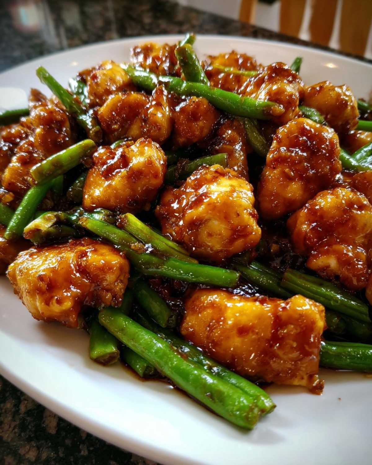 Close-up of glossy, saucy chicken pieces mixed with bright green beans, a perfect chicken and green beans dinner.