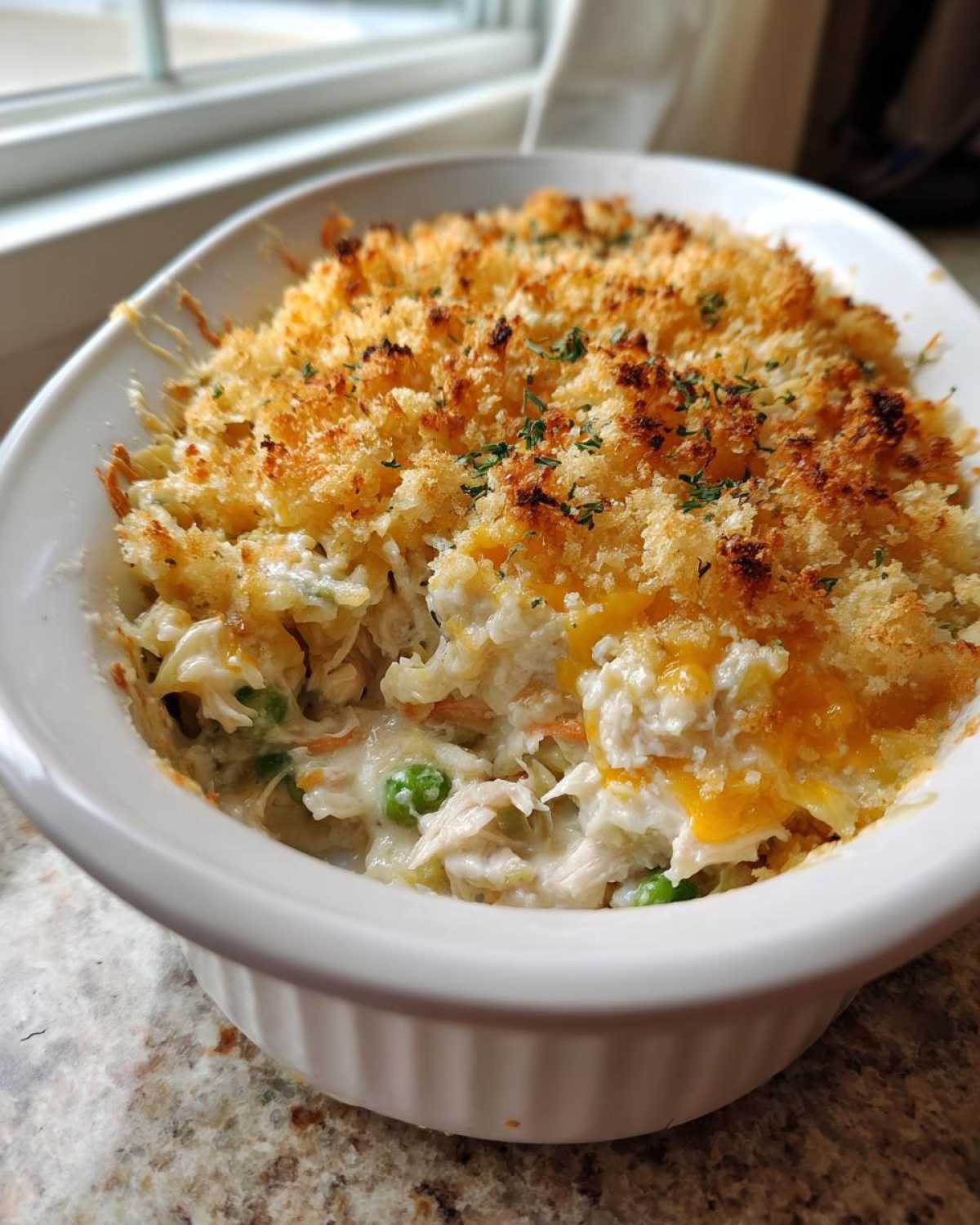 Close-up of a creamy chicken noodle casserole with a golden, crunchy breadcrumb topping and melted cheese.