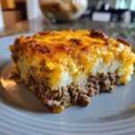 Close-up of a hearty slice of hamburger potato casserole with a layer of seasoned ground beef topped with mashed potatoes and melted cheddar cheese.