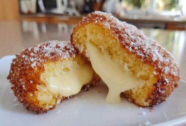 A sweet korean corn dog cut in half, revealing a gooey, melted cheese filling dripping onto a white plate.