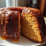 A slice cut from a whole Bacardi rum cake, showing the moist crumb and rich caramel glaze dripping down the sides.