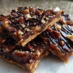 Close-up of stacked slices of rich Pecan Pie Bark with a shortbread crust, caramel, chocolate drizzle, and sea salt.