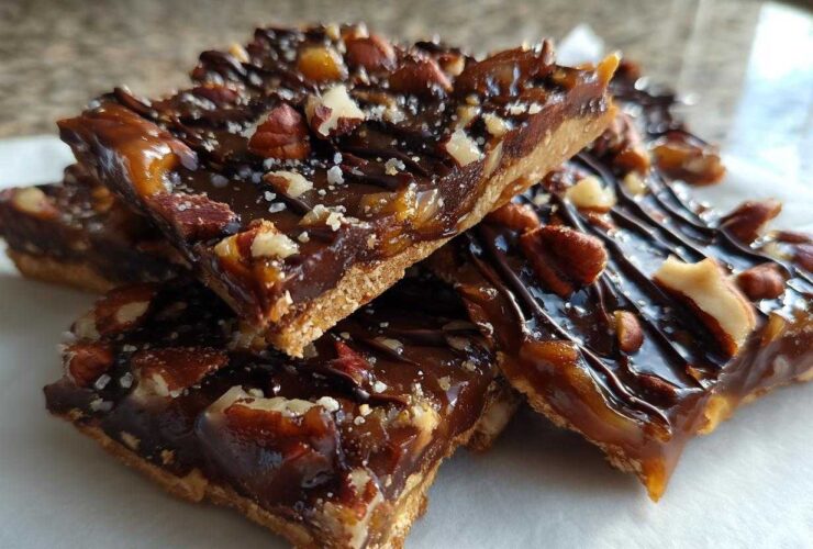 Close-up of stacked slices of rich Pecan Pie Bark with a shortbread crust, caramel, chocolate drizzle, and sea salt.