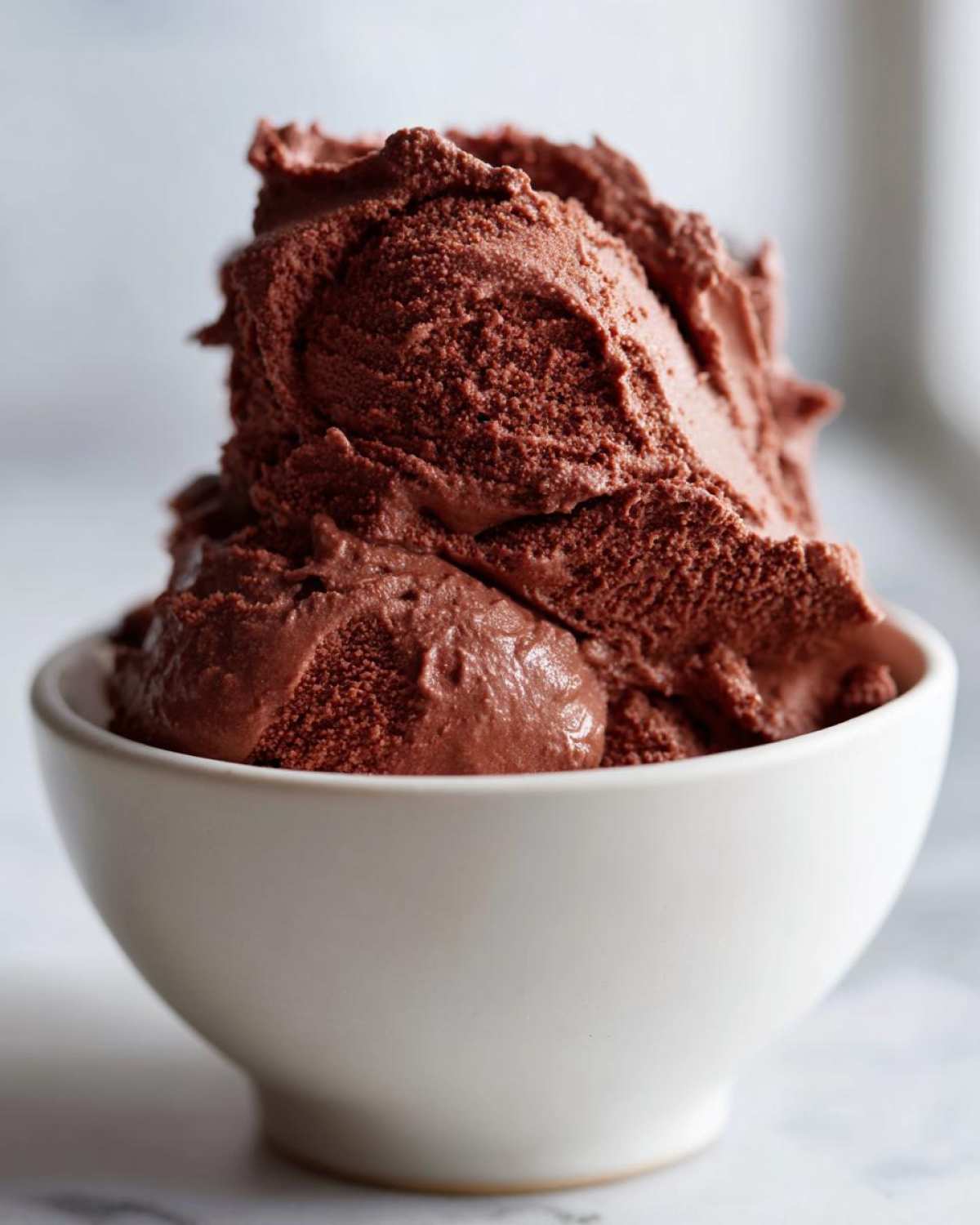 A close-up of rich, dark brown chocolate mousse generously scooped into a small white bowl.