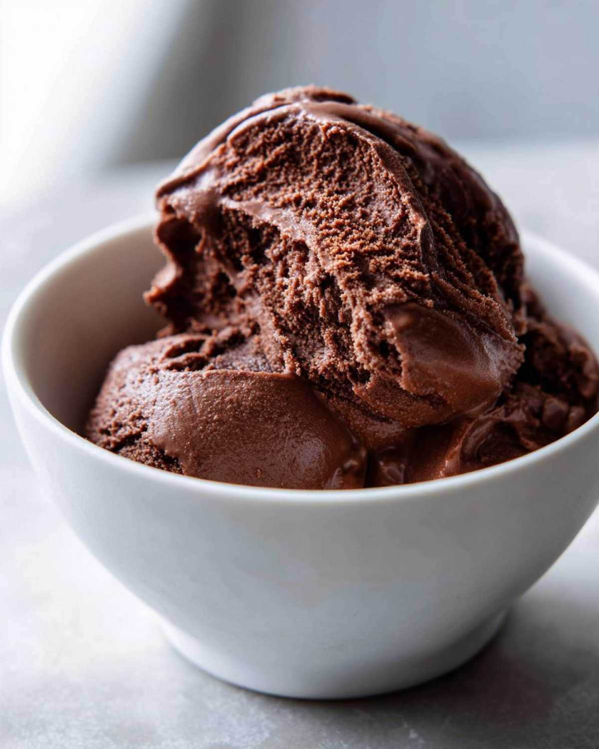 Close-up of two scoops of rich, dark chocolate mousse served in a small white bowl.