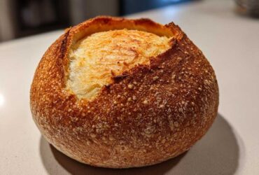 A single, round, crusty loaf ready to be turned into one of our amazing bread bowls, featuring a golden-brown exterior.