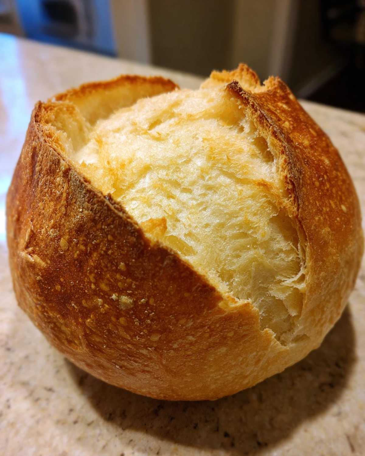 Close-up of a golden-brown, round loaf ready to be used as bread bowls, showing a crisp crust.