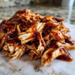 Close-up of shredded crockpot teriyaki chicken piled high and coated in a glossy teriyaki sauce.