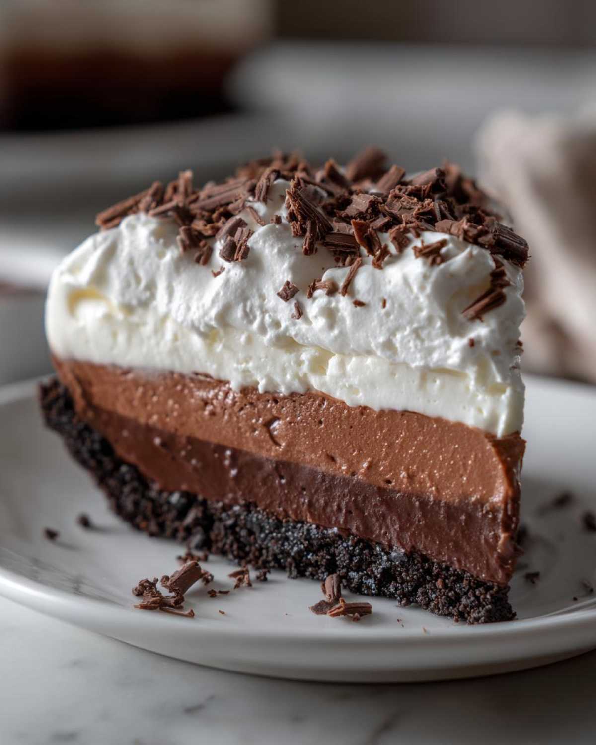 A decadent slice of multi-layered chocolate mud pie topped with whipped cream and chocolate shavings.