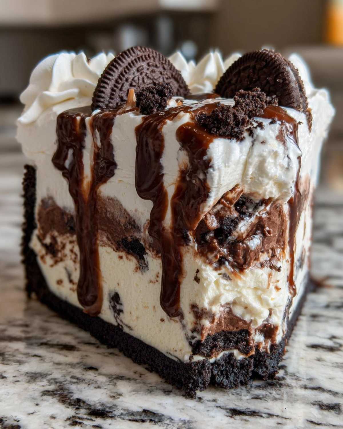 A decadent slice of ice cream pie featuring layers of vanilla and chocolate ice cream, an Oreo crust, topped with whipped cream and chocolate syrup.