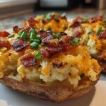 Close-up of delicious twice baked potatoes loaded with melted cheddar cheese, crispy bacon bits, and fresh chives.