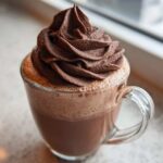 Close-up of a glass mug filled with hot chocolate, topped with a generous swirl of dark chocolate whipped hot chocolate.