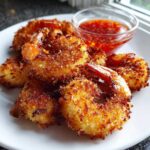 Close-up of golden brown, crispy Air Fryer Coconut Shrimp served on a white plate with sweet chili sauce.