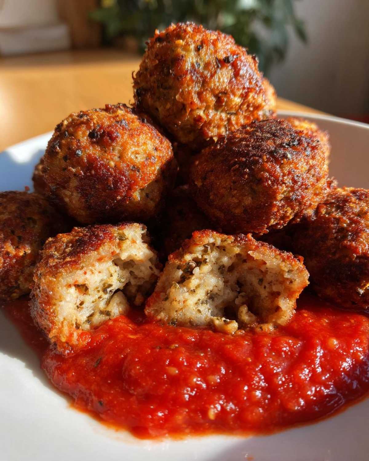 Close-up of golden brown Air Fryer Italian Meatballs piled on a white plate with rich marinara sauce.