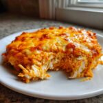A scoop of hot, cheesy Baked Buffalo Chicken Dip showing shredded chicken texture on a white plate.