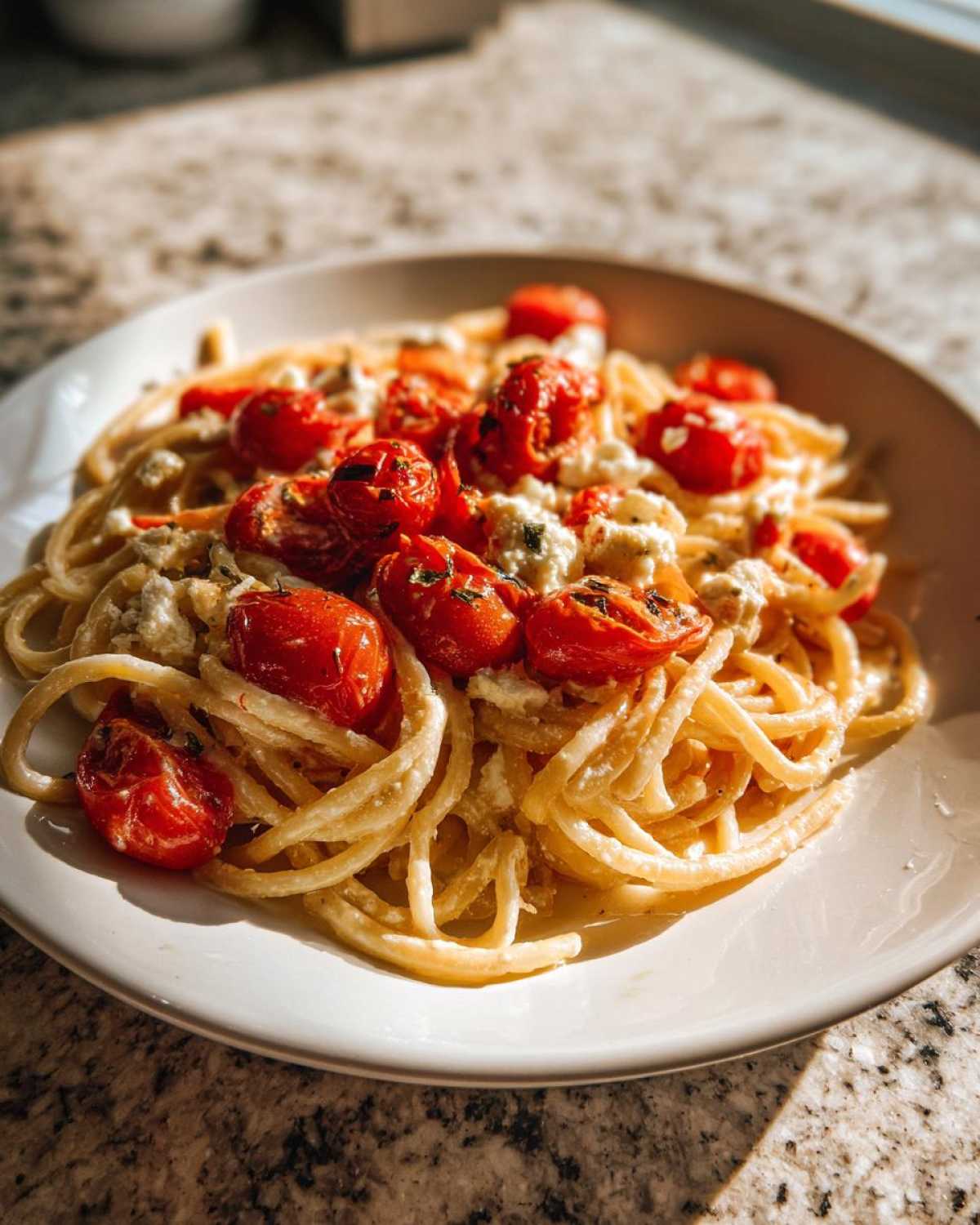 A close-up of a serving of Baked Feta Pasta with Cherry Tomatoes, coated in a creamy sauce.