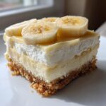 A single serving of Banana Pudding Cheesecake Bars featuring a graham cracker crust, creamy filling, whipped topping, and fresh banana slices.