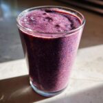 Close-up of a thick, vibrant purple Blueberry Lemon Chia Smoothie in a clear glass.