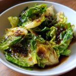 Close-up of stir-fried cabbage wedges coated in a dark, glossy garlic ginger sauce.