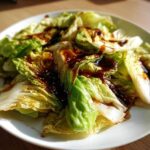 Close-up of Cabbage Stir Fry with Garlic Ginger Sauce, featuring wilted cabbage drizzled with dark sauce and sesame seeds.