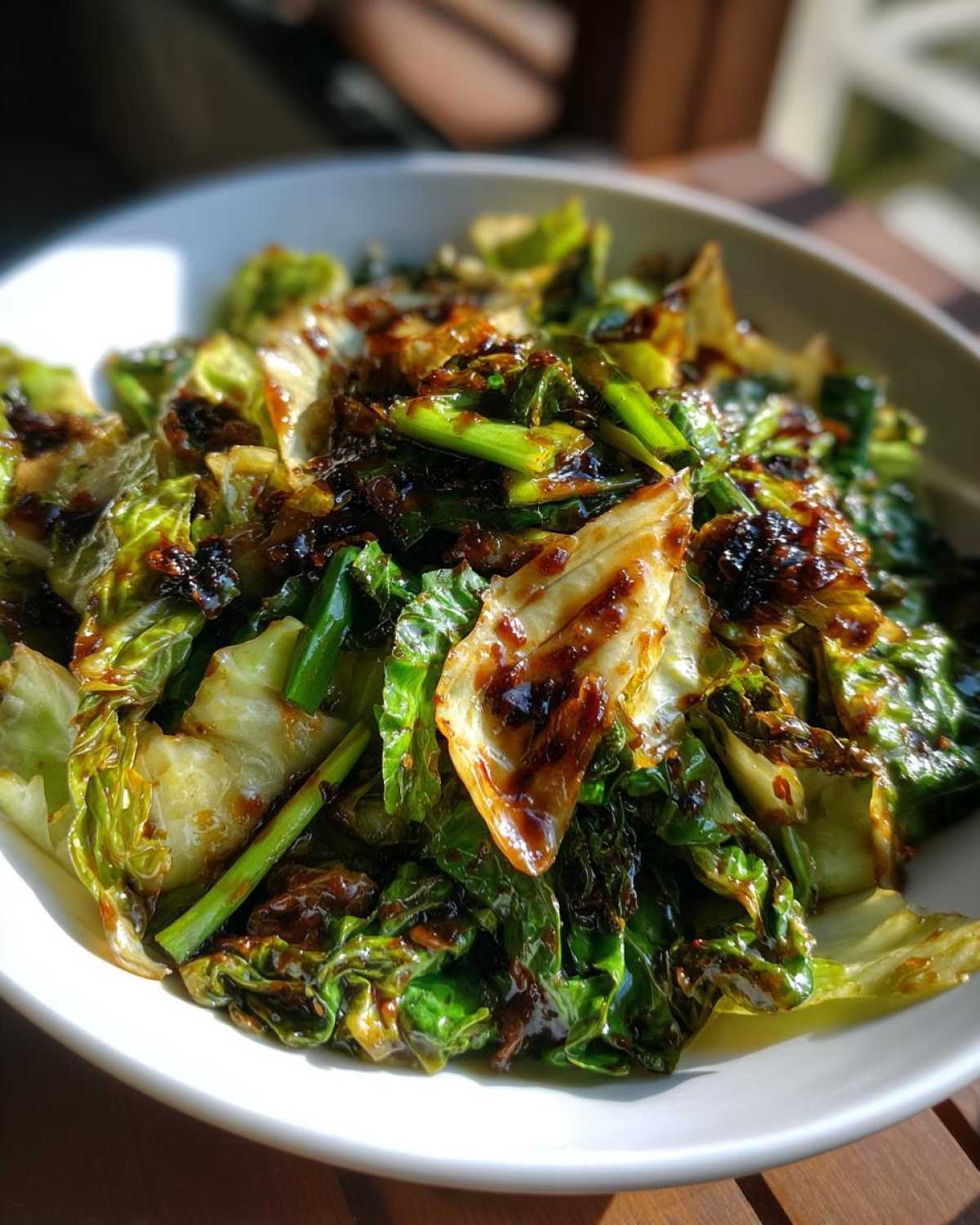 A vibrant bowl of Cabbage Stir Fry with Garlic Ginger Sauce, showing caramelized edges and glossy green leaves.