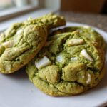 Close-up of three chewy matcha white chocolate cookies stacked slightly on a white plate.