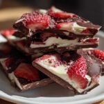 A stack of rich Chocolate Covered Strawberry Bark pieces featuring dark chocolate, white filling, and fresh strawberry slices.