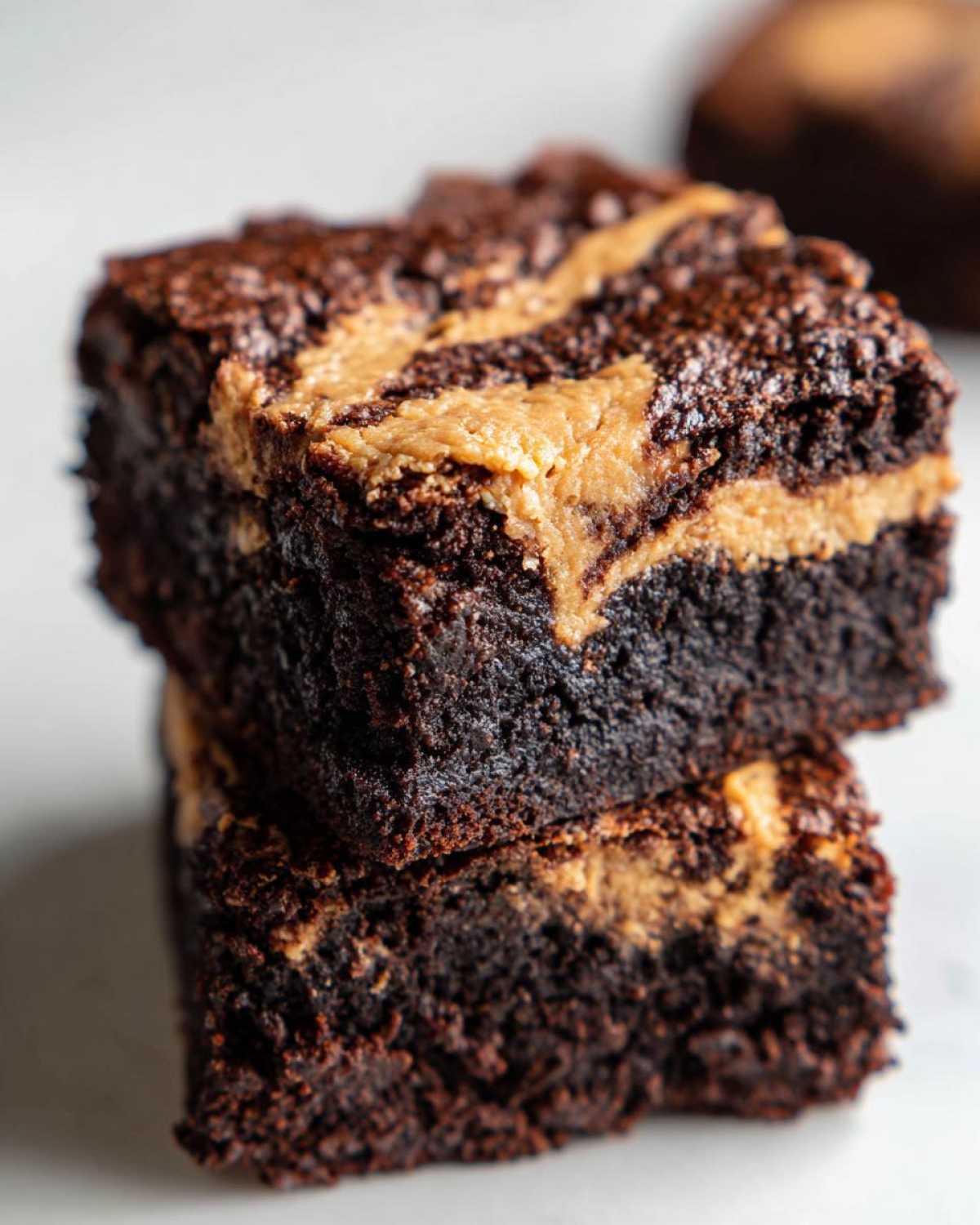 Two fudgy Dark Chocolate Tahini Brownies stacked, showing a rich dark interior and a light tahini swirl on top.