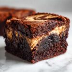 Close-up of a fudgy Dark Chocolate Tahini Brownies square with a beautiful tahini swirl on top.