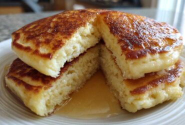 Close-up of fluffy Gluten-Free Buttermilk Pancakes cut open, showing the interior texture and syrup.