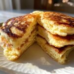 Close-up of a stack of fluffy Gluten-Free Buttermilk Pancakes cut in half, showing the moist interior and melting butter.