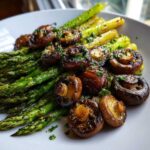 Close-up of roasted asparagus spears topped with glossy, browned mushrooms seasoned with parsley.