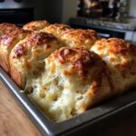 Close-up of freshly baked Garlic Parmesan Pull-Apart Bread with melted, stringy cheese stretching between the rolls.