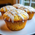 Close-up of a freshly baked Glazed Lemon Poppy Seed Muffin topped with thick white icing and poppy seeds.