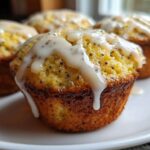 Close-up of a freshly baked Glazed Lemon Poppy Seed Muffin with thick white icing dripping down the side.