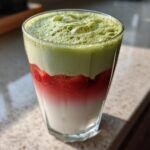 Close-up of a beautiful Iced Strawberry Matcha Latte showing distinct layers of milk, strawberry puree, and green matcha foam.