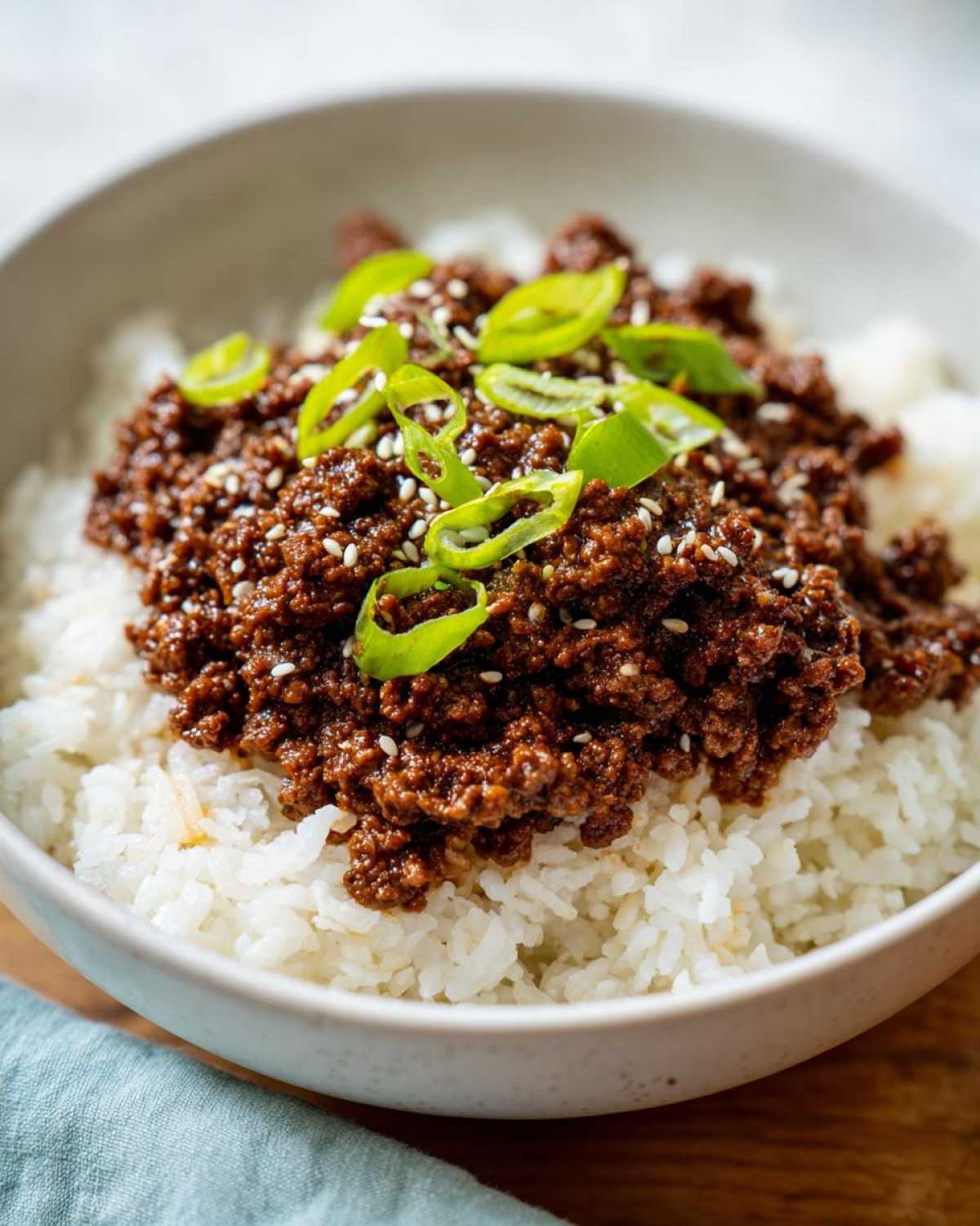 Close-up of Korean Ground Beef Bulgogi Bowls featuring savory ground beef over white rice, topped with green onions and sesame seeds.