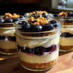 Four individual Lemon Blueberry Cheesecake Jars layered with graham cracker crust, cream cheese filling, and fresh blueberries.