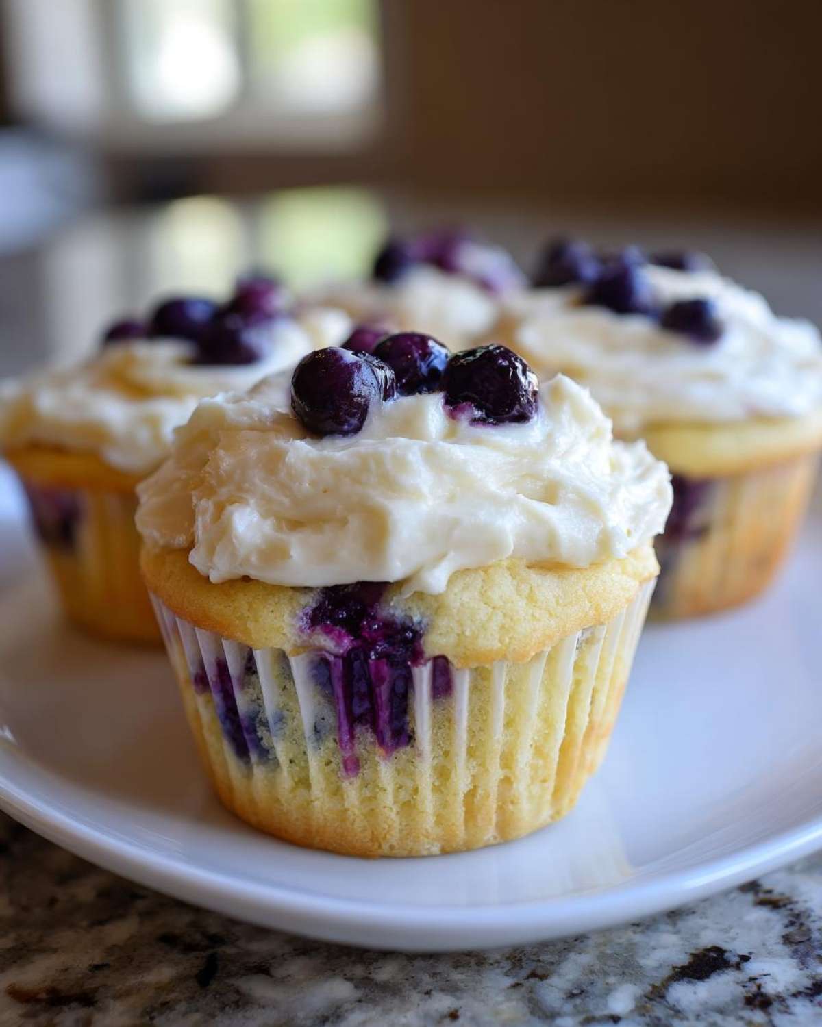Close-up of a Lemon Blueberry Cupcake with thick cream cheese frosting and fresh blueberries on top.