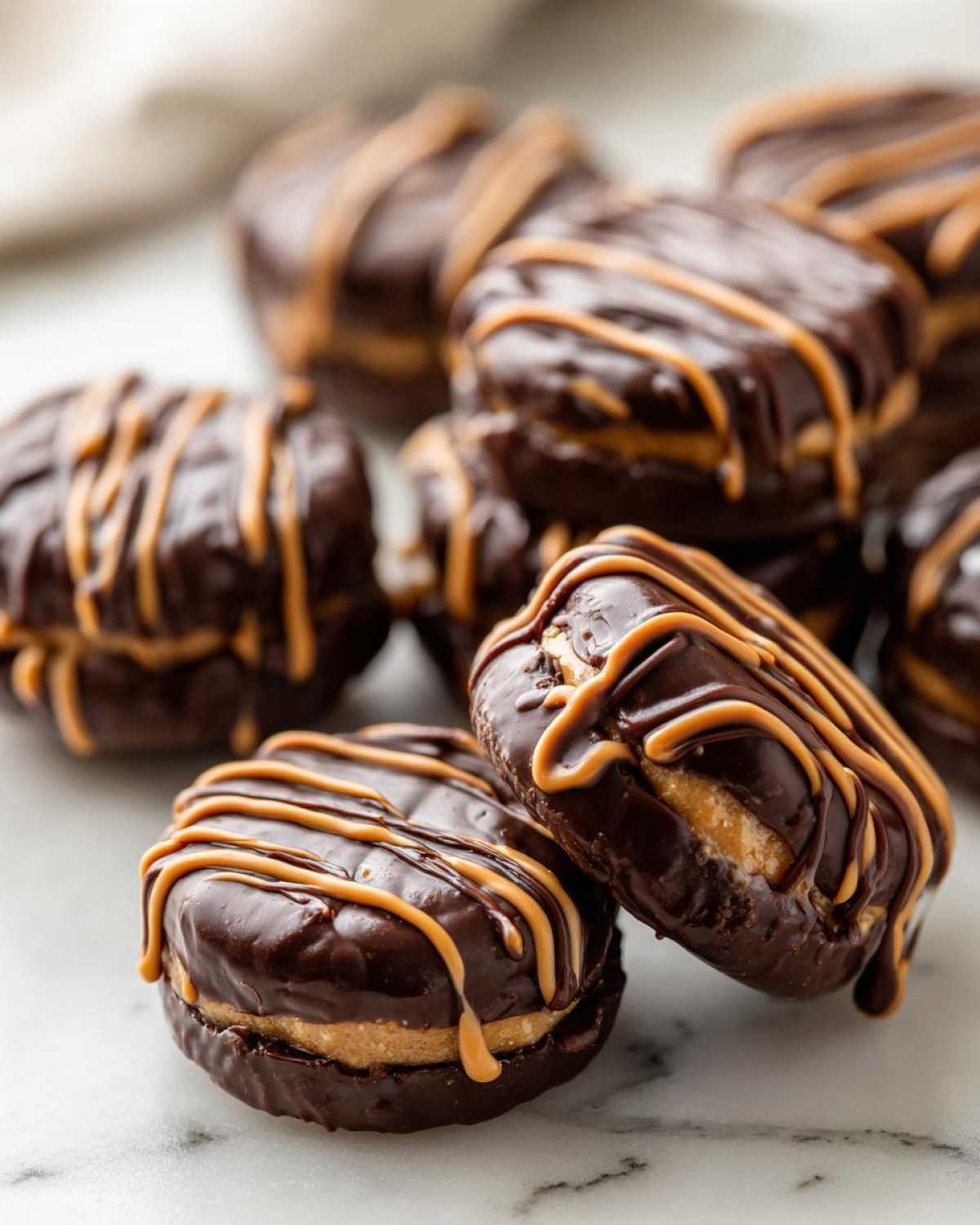 Close-up of several No-Bake Chocolate Covered Banana Bites stacked, drizzled with peanut butter or caramel.