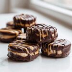 A stack of rich No-Bake Chocolate Covered Banana Bites drizzled with peanut butter or caramel.
