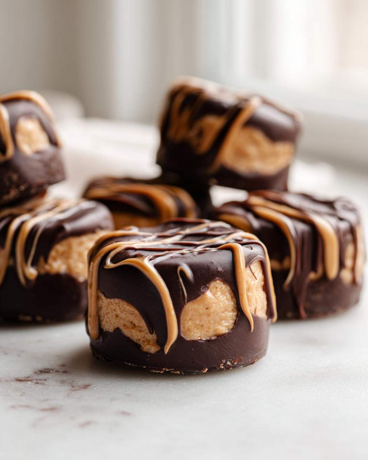 Close-up of No-Bake Chocolate Covered Banana Bites coated in dark chocolate and drizzled with peanut butter.