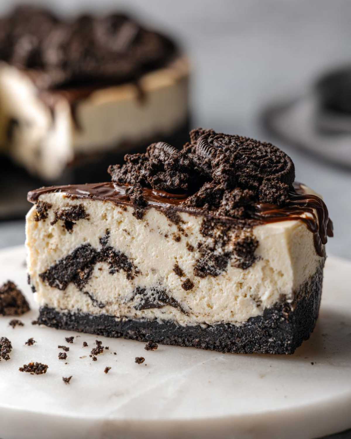 A generous slice of No-Bake Oreo Cheesecake featuring a dark cookie crust and creamy filling loaded with cookie pieces.